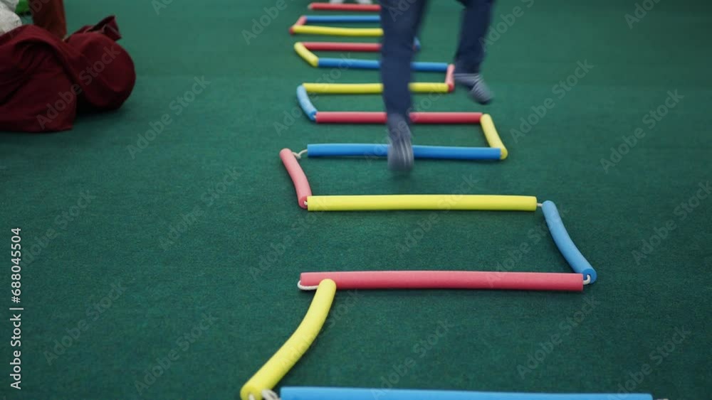 Children's games. A little boy jumps inside a figure made of rope with colorful tubes on it. Hand held. Children's games. A little boy jumps inside a figure made of rope with colorful tubes on it. Hand held.