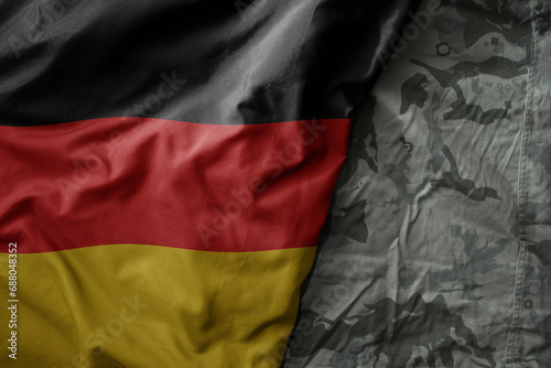 waving flag of germany on the old khaki texture background. military concept.