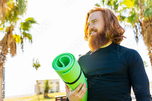handsome redhaireb man with long beard wear black sporty suit ready for yoga meditation in sunny beach