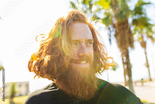 handsome redhaireb man with long beard wear black sporty suit and warming up in sunny beach photo