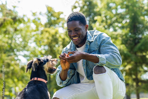latin american man walking with his cute dog at sunny day in city park lawn on the grass