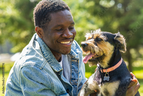 latin american man walking with his cute dog at sunny day in city park lawn on the grass photo