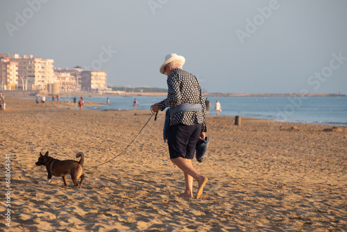 Hombre mayor pasea a su mascota junto al mar