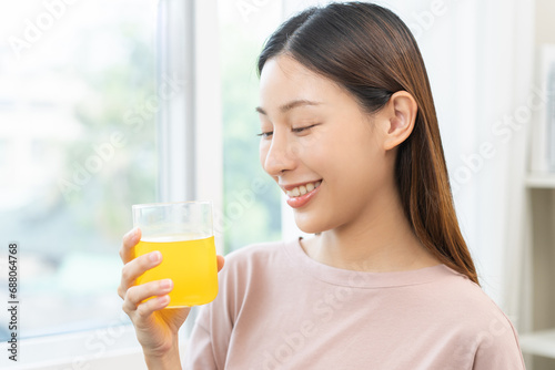 Smile asian young woman, girl hand holding a glass of water after putting or dropping yellow effervescent tablet, painkiller medicine, aspirin for treatment, take vitamin c for hangover, health care.