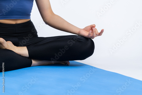 Cropped woman in sportswear doing yoga exercise on fitness mat as her workout training routine. Healthy body care and meditation in yoga lifestyle in studio shot on isolated background. Vigorous