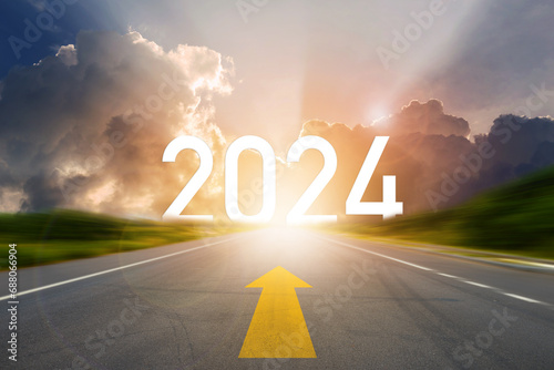 Go to the New Year 2024. Happy New Year greeting card 2024, 2024 letters on the highway road in the destination with arrow on asphalt road with sunset or sunrise light above asphalt road. photo