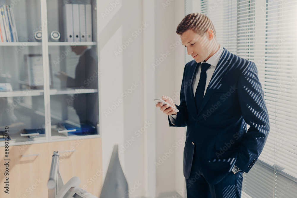 Serious businessman with phone, blinds casting shadows Serious businessman with phone, blinds casting shadows