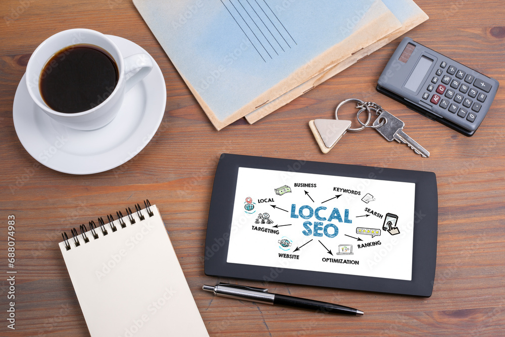 Local Seo Concept. Illustration with icons, arrows and keywords. Tablet device on a wooden table