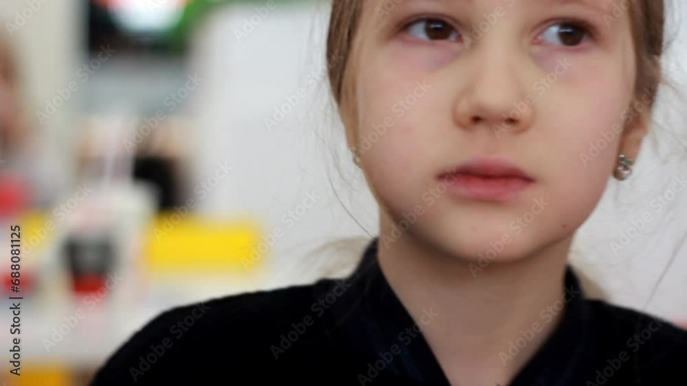 Close-up portrait of a little girl in a fast food cafe eating a hamburger. Hungry cute child eating a burger. Close-up portrait of a little girl in a fast food cafe eating a hamburger. Hungry cute child eating a burger.