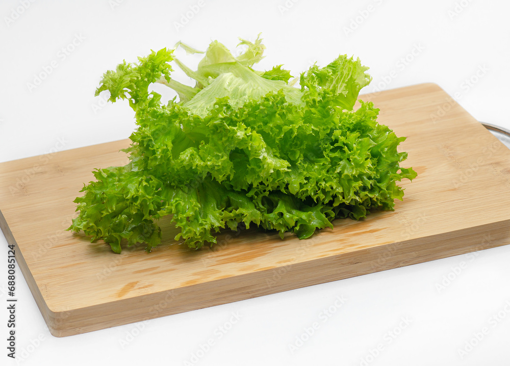 Green salad leaves on wooden cutting board. Side view. Preparing a salad for snack. Green salad leaves on wooden cutting board. Side view. Preparing a salad for snack.