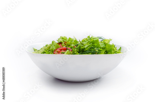 Side view of white bowl with vegetables isolated on white background. Green salad, dill, tomato.