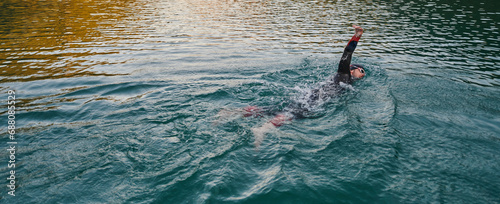 A professional triathlete trains with unwavering dedication for an upcoming competition at a lake, emanating a sense of athleticism and profound commitment to excellence.