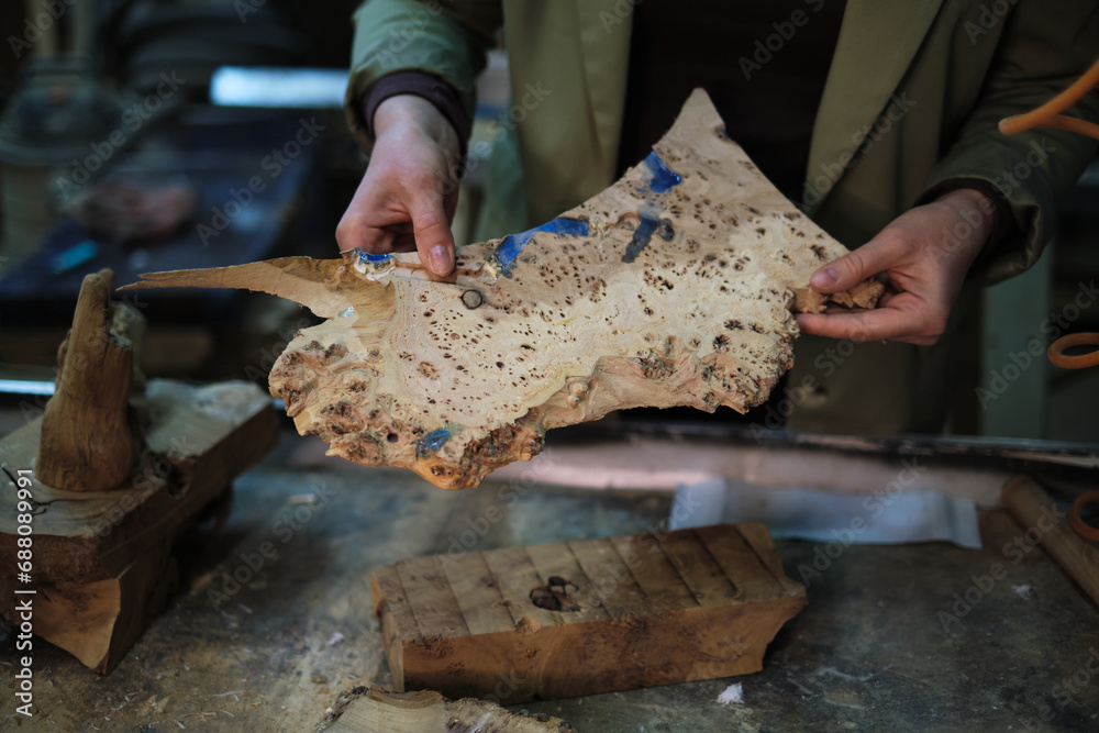 The detailed surface of the wood is inspected closely, showcasing the value placed on unique wood grains in the art of custom woodworking. The detailed surface of the wood is inspected closely, showcasing the value placed on unique wood grains in the art of custom woodworking.