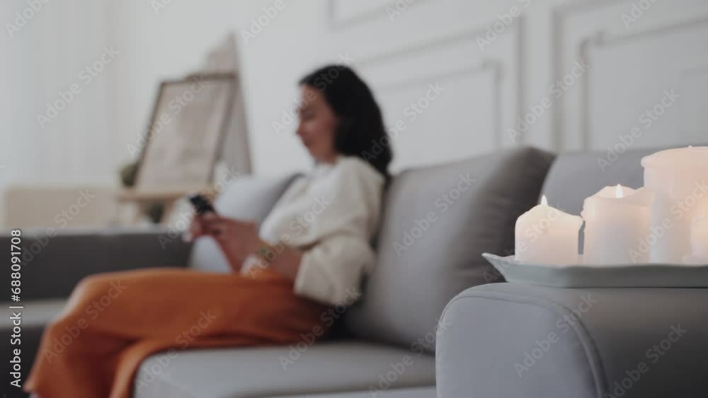 Woman using cellphone in living room with burning candles Woman using cellphone in living room with burning candles