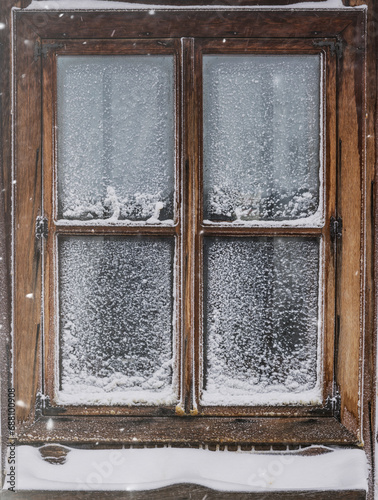 Verschneites altes Holzfenster mit zugefrorener Fensterscheibe