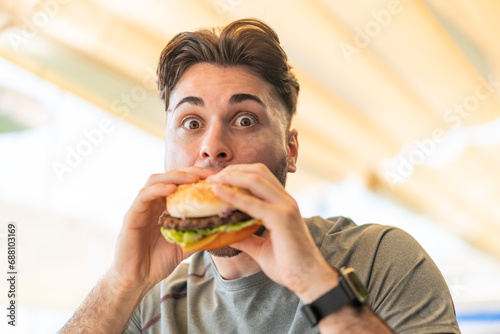 Young handsome man holding a burger