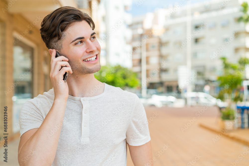 Young handsome man keeping a conversation with the mobile phone with someone Young handsome man keeping a conversation with the mobile phone with someone