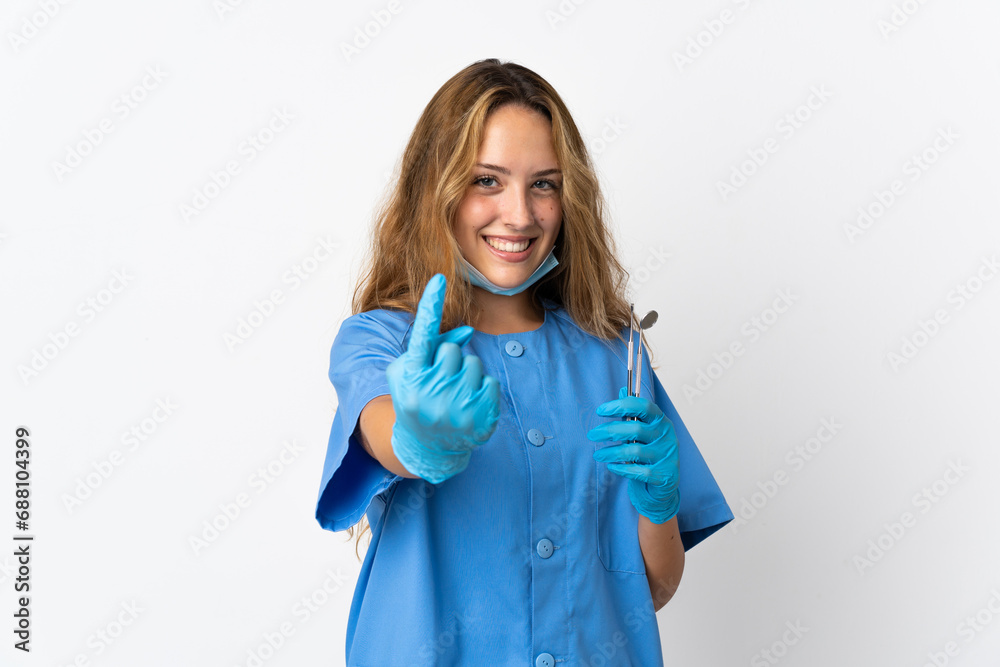 Woman dentist holding tools isolated on white background doing coming gesture Woman dentist holding tools isolated on white background doing coming gesture