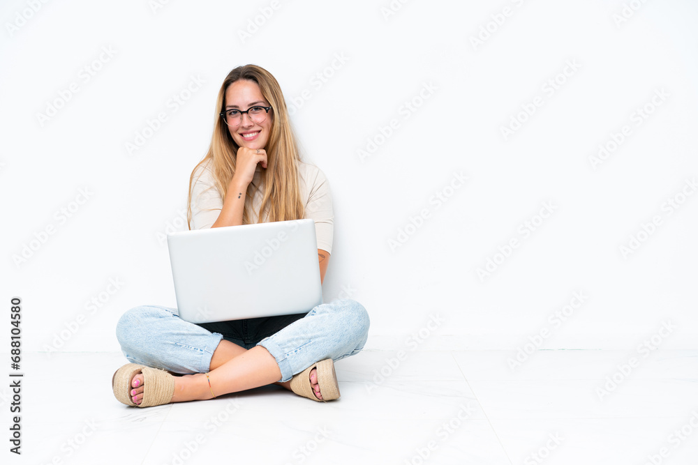 Young woman with laptop sitting on the floor isolated on white background with glasses and smiling Young woman with laptop sitting on the floor isolated on white background with glasses and smiling