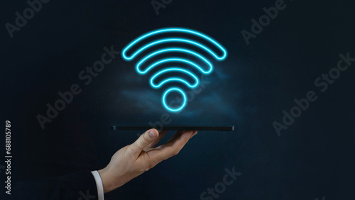 Wi Fi blue neon symbol, wireless networking digital hi tech innovation concept, free internet zone and hotspot, hologram above digital tablet on man hand