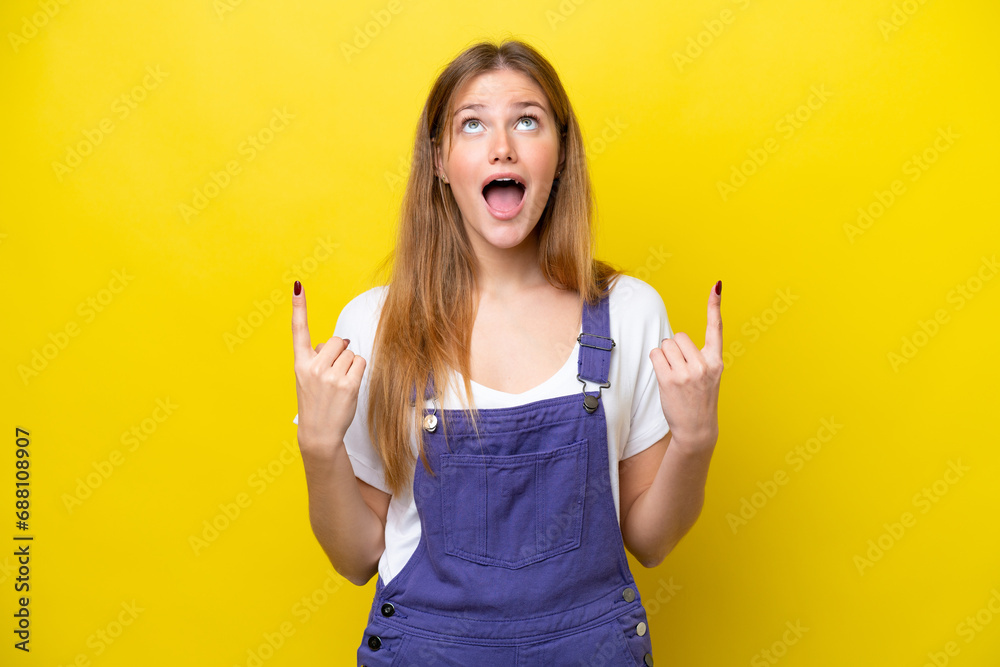 Young caucasian woman isolated on yellow background surprised and pointing up Young caucasian woman isolated on yellow background surprised and pointing up
