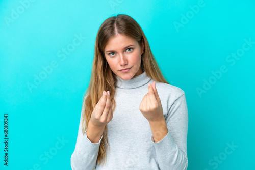 Young blonde woman isolated on blue background making money gesture but is ruined