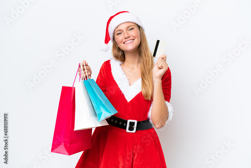 Young caucasian woman dressed as mama noel isolated on white background holding shopping bags and a credit card