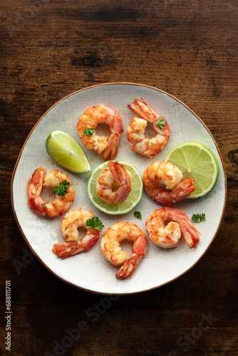 Shrimps, top shot. Cooked shrimp with lime on a white plate on a rustic wooden table. Spanish cuisine