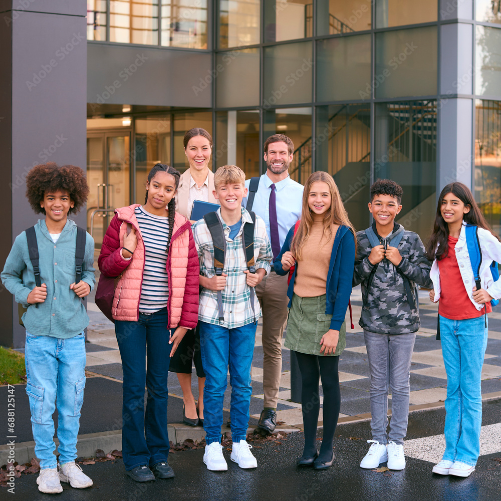 Fototapeta premium Portrait Of Class Of Secondary Or High School Pupils Standing Outside School Building With Teachers