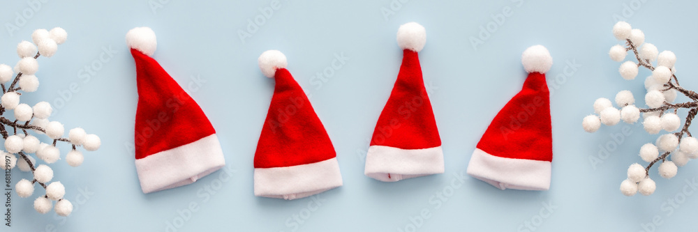 Santa Claus hats and rowan branches on a blue background, Christmas background, Merry Christmas and Happy New Year banner, top view, copy space Santa Claus hats and rowan branches on a blue background, Christmas background, Merry Christmas and Happy New Year banner, top view, copy space