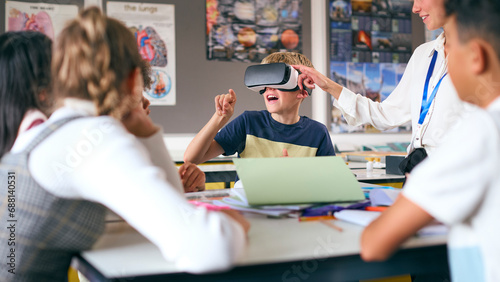 Amazed Male Secondary Or High School Pupil Wearing VR Headset In Science Class With Female Teacher