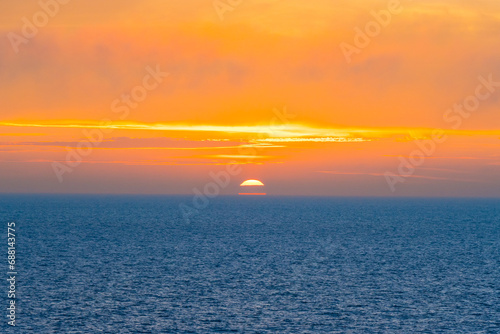 Beautiful Sunset in the Atlantic Ocean with orange sky and blue ocean somewhere in Faroe Islands