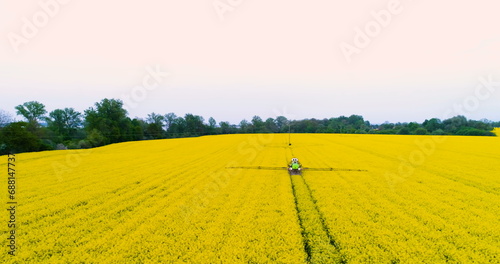 Tractor spraying oilseed rape field. Agriculture background. Aerial view. 4K