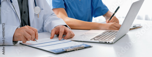 Professional various team of medical working and planning medical treatment at hospital table together. Teamwork lead to successful illness and sickness treatment. Panorama Rigid photo