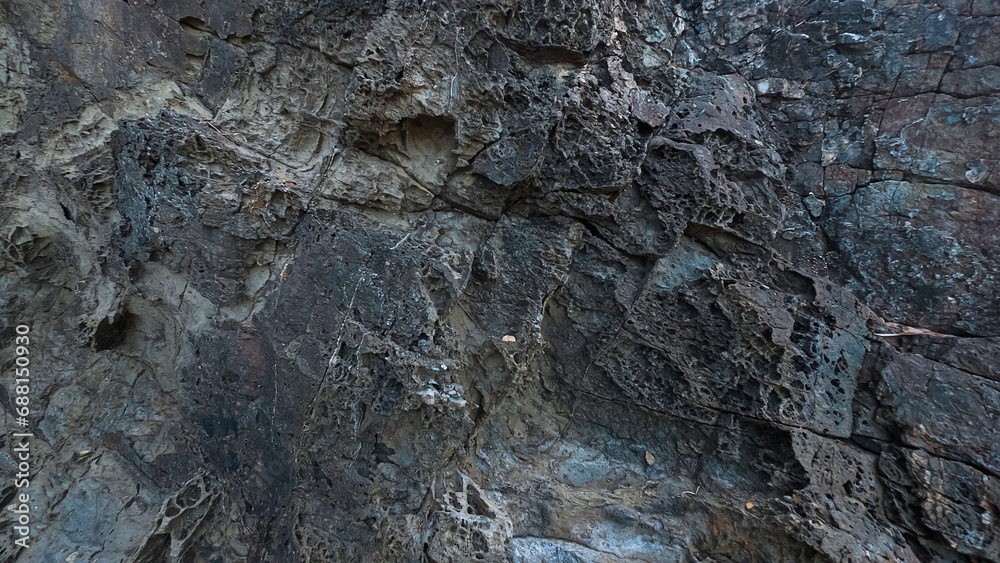 A rough rocky texture with cracks, stains and wholes on displaced surface of stone A rough rocky texture with cracks, stains and wholes on displaced surface of stone