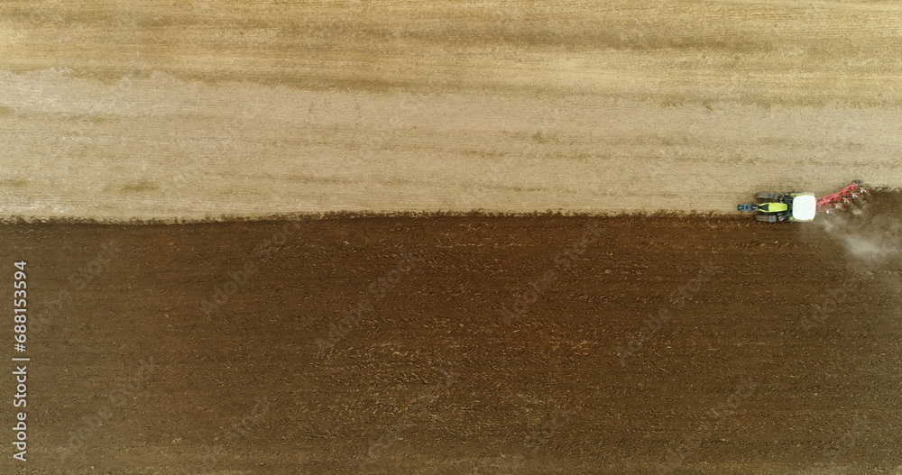 Obraz premium Aerial view of tractor plowing field.