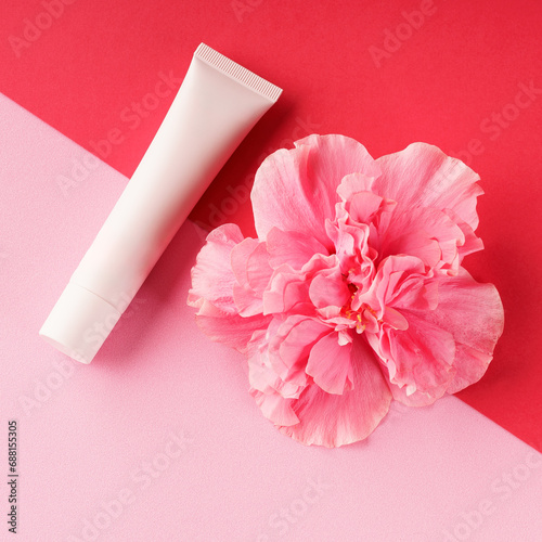 fleur rose sur fond rouge et rose, avec tube de crème