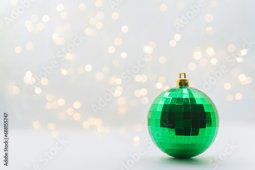 New Year photo. Two Christmas ornaments, one green and one gray, against a white background with a yellow-glowing garland.
