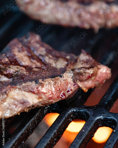 Rumpsteak is cooked on a charcoal grill on a cast iron grate. Close-up.