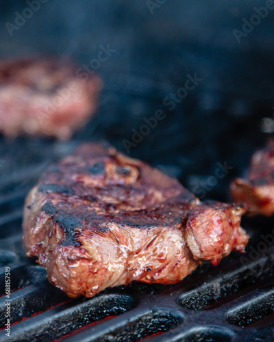 Rumpsteak is cooked on a charcoal grill on a cast iron grate. Close-up.