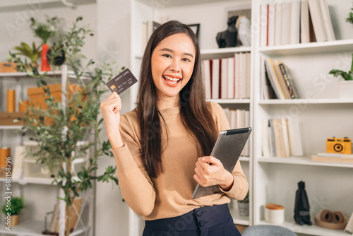 Happy Young woman holding credit card for Online shopping with tablet at workplace. Businesswoman using internet banking for order Product.