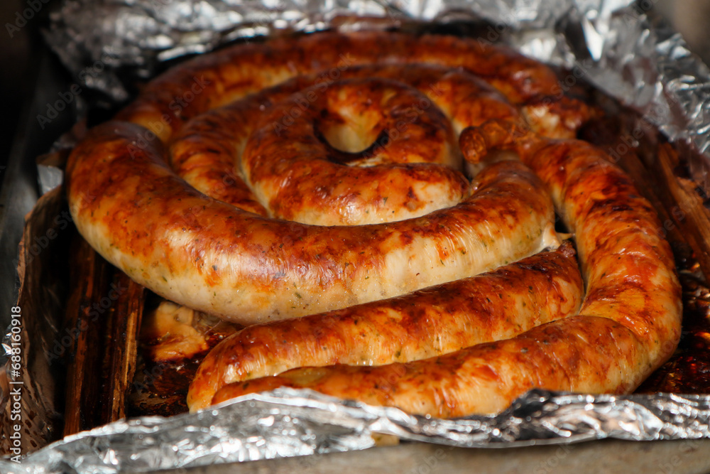 Homemade spiral sausage fried in a wood-burning stove. Meat cooking in a brick oven. Homemade spiral sausage fried in a wood-burning stove. Meat cooking in a brick oven.
