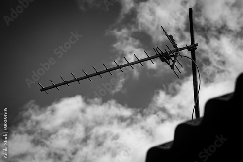 Television antenna on the roof of the house on the background of the sky with clouds photo