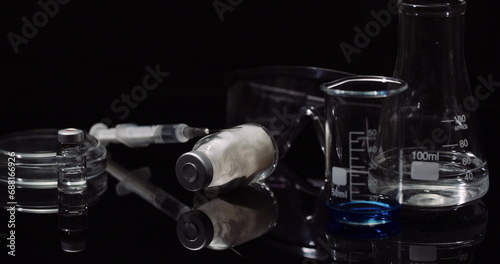 Laboratory Equipement: Syringe and Medicine, Test Tubes and Flasks Rotating on Black Background.