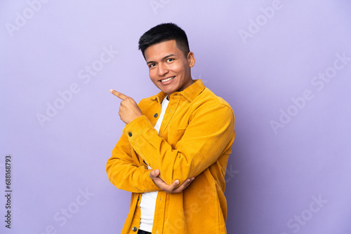 Young Ecuadorian man isolated on purple background pointing finger to the side