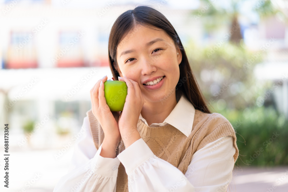 Pretty Chinese woman at outdoors holding an apple Pretty Chinese woman at outdoors holding an apple