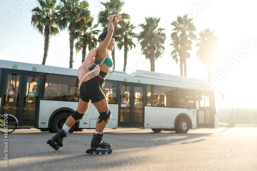 A sporty girl on roller skates against the background of the city in the sunset light on a summer day photo