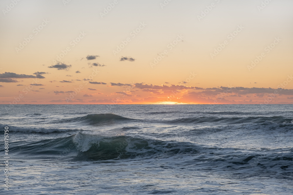 Naklejka premium The sea's waves on the sun set with a dramatic cloudy sky over the Mediterranean Sea. horizon with a warm, golden glow. magical tranquil seascape