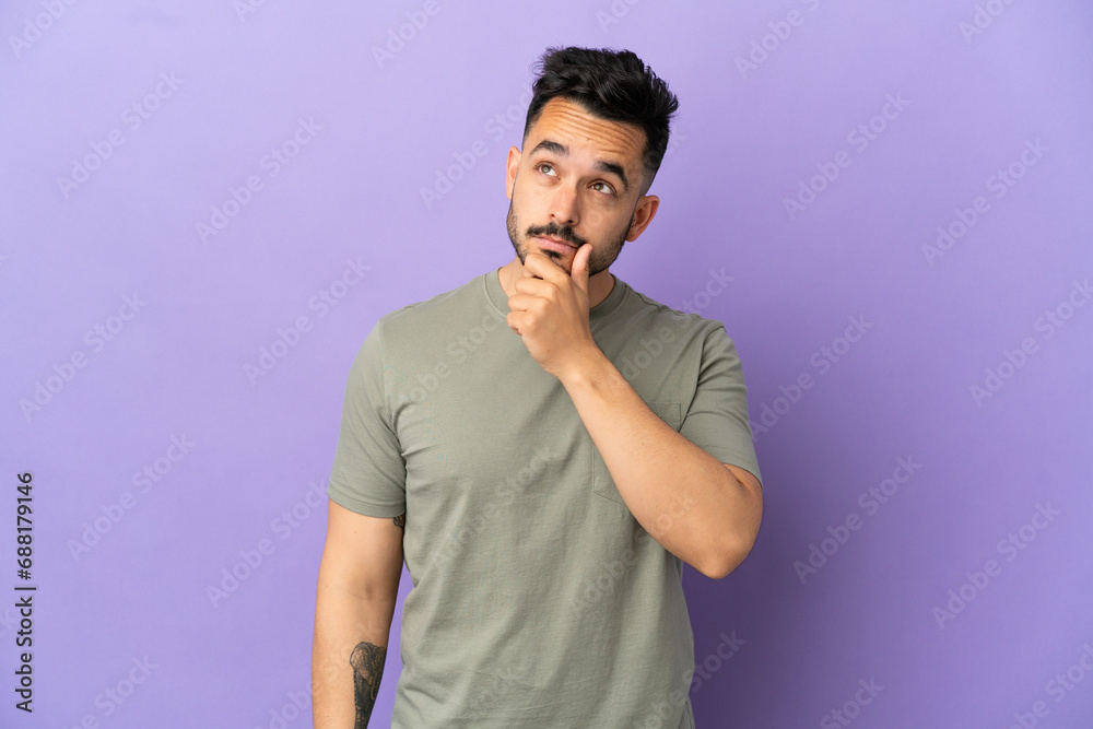 Young caucasian man isolated on purple background having doubts and with confuse face expression