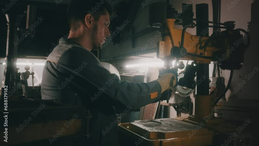 A worker works on a metal drilling machine in a workshop. Metallurgy production. A machinist operating a traditional non-CNC milling machine in a machine shop. Operates an industrial machine. 4K